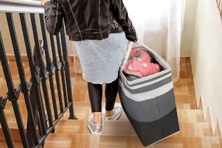 a woman carrying a laundry hamper down the stairs