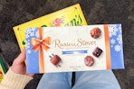 hand holding whitman's and russell stover chocolates