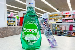 toothpaste leaning against bottle of mouthwash on store counter