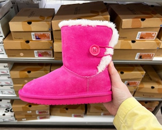 a hand holding up a pink koolaburra by ugg kids boot