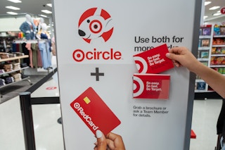 A person taking a brochure from the Target Circle and RedCard information stand inside Target.