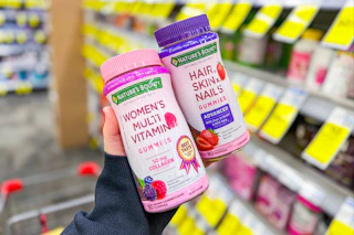 person holding 2 bottles of hair skin nails gummies in an aisle