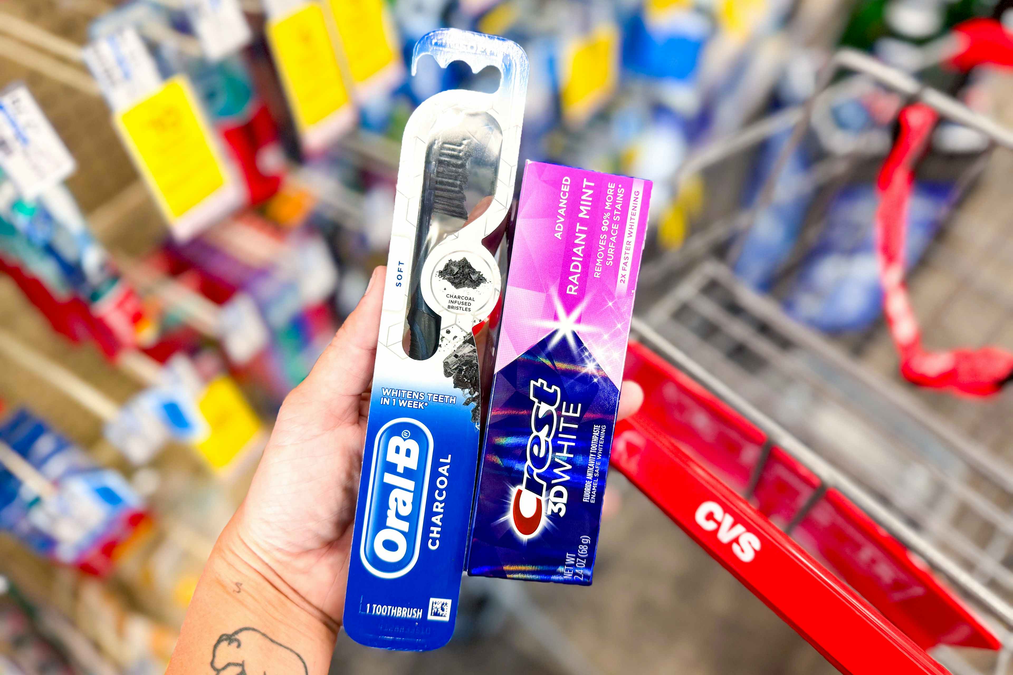 hand holding crest and oral-b products by a cvs shopping cart