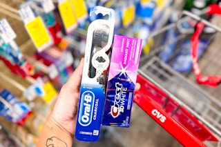 hand holding crest and oral-b products by a cvs shopping cart