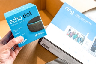 a person taking an echo dot out of an amazon package with a ring video doorbell in the background