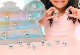 a child holding a couple of silver Disney100 Doorables with a display next to them with more Doorables sitting on the shelves