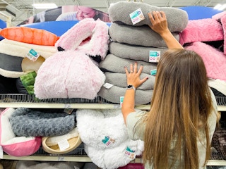 a stack of cat beds that a woman is pulling one down