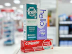 toms, hello, and colgate toothpastes on a shelf
