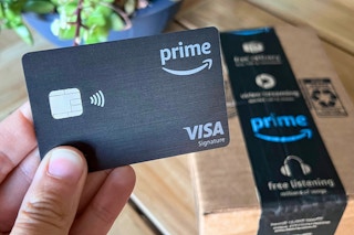 someone holding a amazon prime visa credit card in front of a package