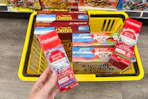 hand holding up colgate toothpaste over yellow shopping basket