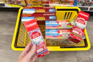 hand holding up colgate toothpaste over yellow shopping basket