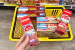 hand holding up colgate toothpaste over yellow shopping basket