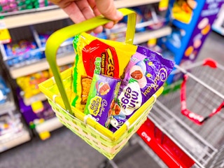 hand holding a yellow easter basket with reese's and cadbury candy