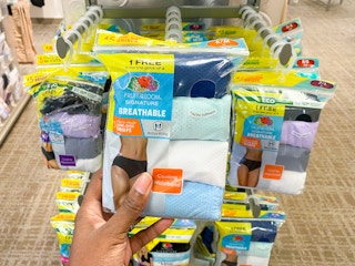 a pack of fruit of the loom underwear being held in front of a display of other packs of underwear