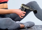 a person using a massage gun on their leg