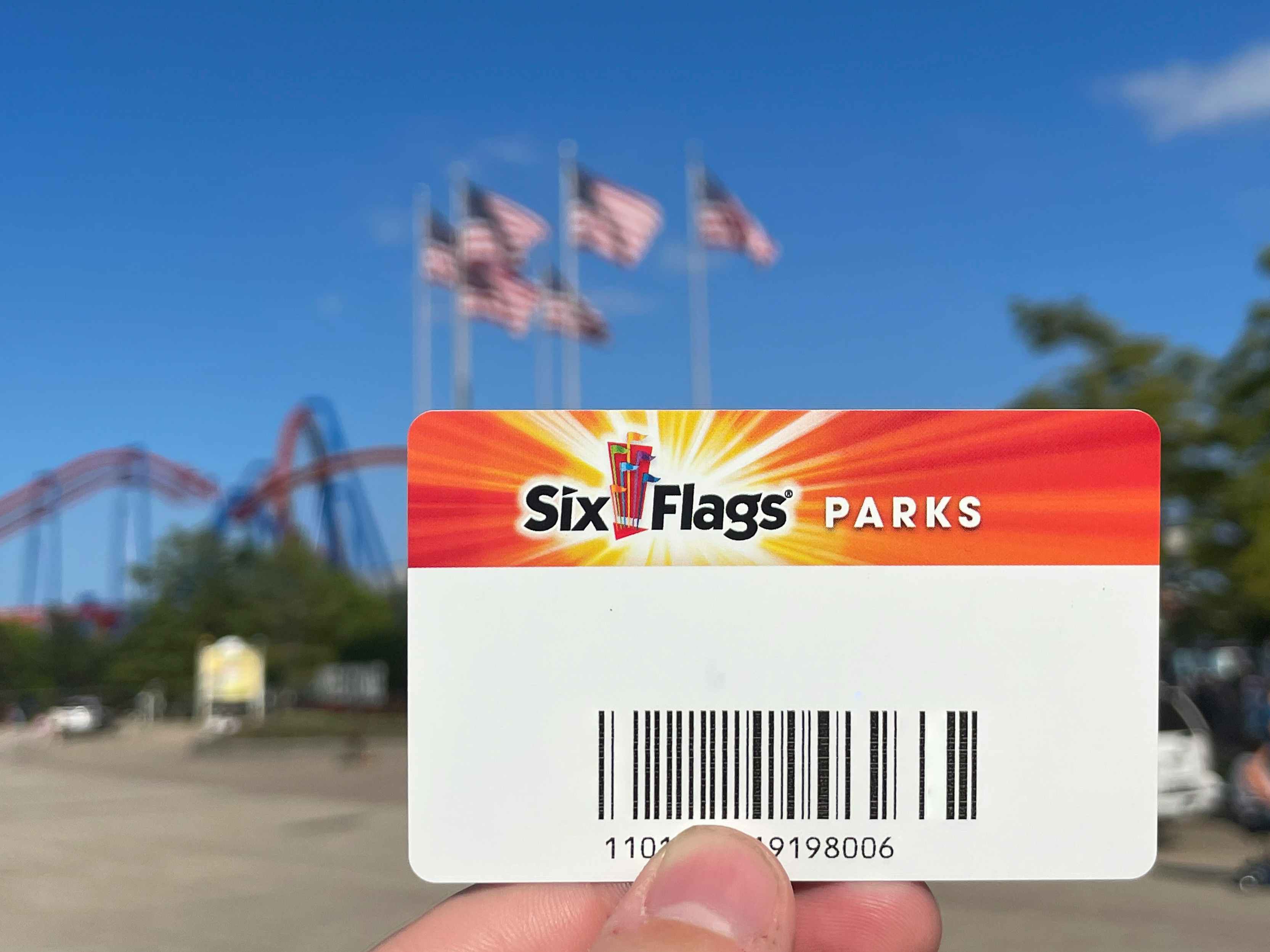 Is six flags amusement park season pass held in front of the park. American flags can be seen on flag poles in the background.