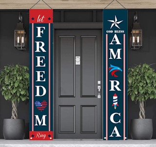 Two ourth of july banners hanging in front of a house's front door