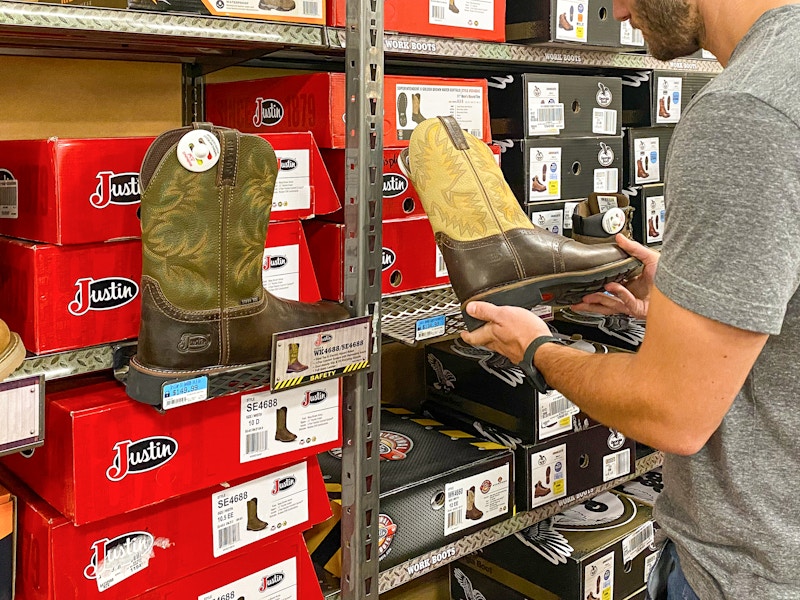 A man looking at Justin boots inside Tractor Supply.