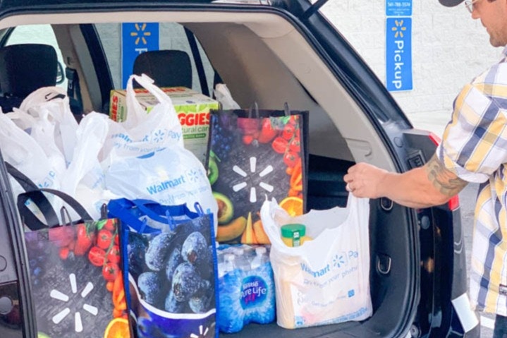 man loading walmart grocery pickup in back of car