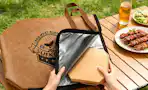 a hand putting a plate of meat in a meat resting bag