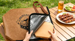 a hand putting a plate of meat in a meat resting bag