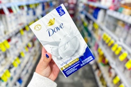 person holding a pack of dove bar soap in an aisle