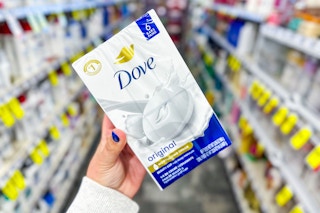 person holding a pack of dove bar soap in an aisle