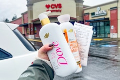 hand holding two dove body washes and a cvs receipt outside of a cvs store