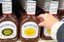 hand reaching for a bottle of sweet baby ray's barbecue sauce