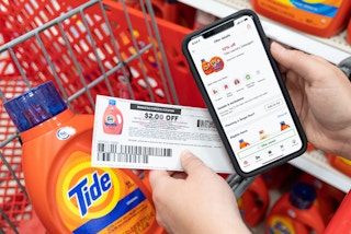 A person's hands holding a cell phone displaying 10% off Tide laundry detergent on the target circle app and a $2 off manufacture coupon,...