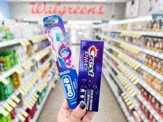 hand holding crest toothpaste and oral-b toothbrush