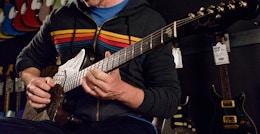 person playing a guitar inside of a guitar center