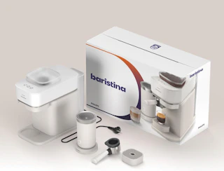 a espresso machine and milk frother next to its packaging