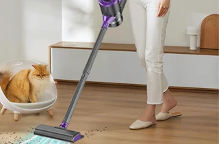 a person vacuuming crumbs of a hardwood floor