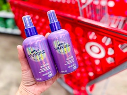 hand holding 2 aussie daily hair mist treatments in front of target cart