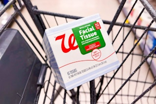 person placing a box of tissues in a cart