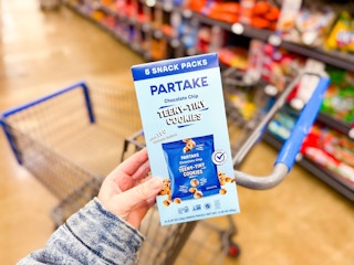 hand holding a box of partake teeny cookies over walmart cart