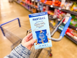 hand holding a box of partake teeny cookies over walmart cart