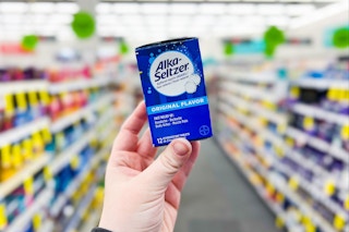 person holding a box of alka-seltzer tablets in an aisle