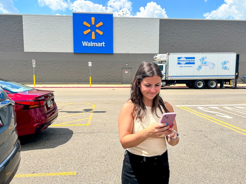 a person looking at their phone outside of walmart