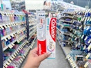 hand holding colgate toothpaste and toothbrush in walgreens