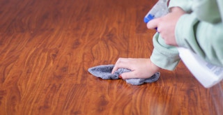 a person cleaning hardwood floors with cleaning solution and a small towel