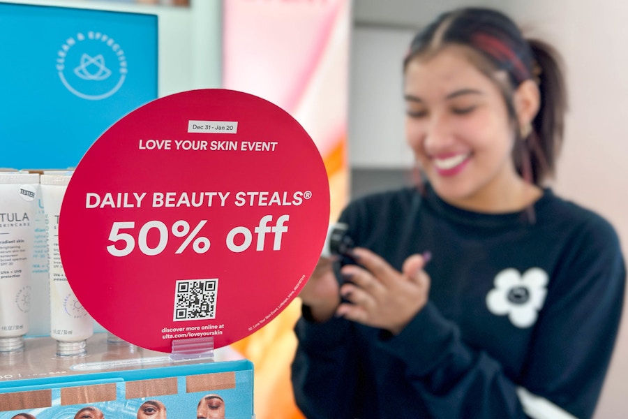 a woman standing behind a sales sign testing makeup in ulta