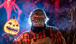 a monster holding a glowing pumpkin outside