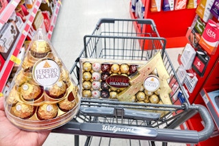 hand holding ferrero rocher gift set in front of basket filled with ferrero rocher gift boxes